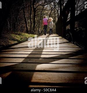 Two girls walking along board walk in woods Stock Photo