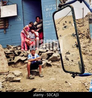 Peruvian family members sit in front of a wooden house on the dusty hillside of Pachacútec, a desert shantytown in Lima, Peru, 20 January 2015. Stock Photo