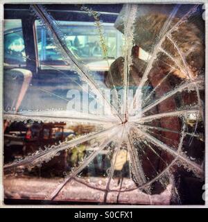 Starburst pattern in shattered window glass on an old car in a junk yard. Stock Photo
