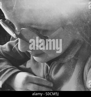 Little girl looking down towards a screen in a concentrated manner Stock Photo