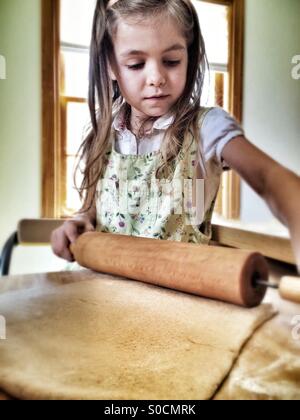 girl helping roll out french bread dough Stock Photo