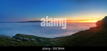 The sun setting over the Snowdonia mountain range, Wales, featuring sea mist. Shot from the Great Orme, Llandudno Stock Photo