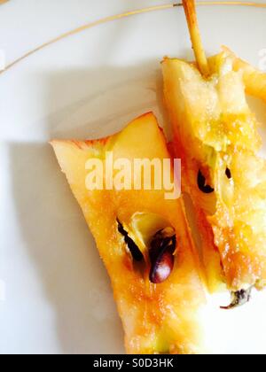 Two discarded apple cores on a white plate Stock Photo