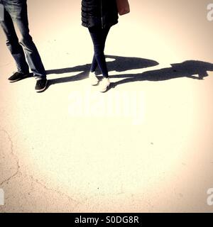Couple standing on concrete on sunny day with shadow being cast