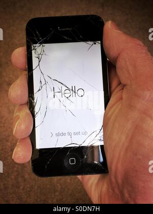 Hand holding iPhone 4S with broken screen Stock Photo