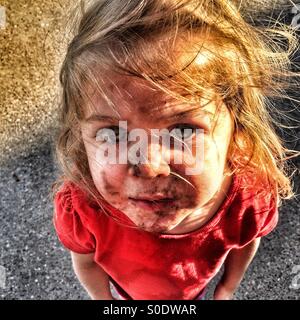 Child with a dirty face and windswept hair looking up