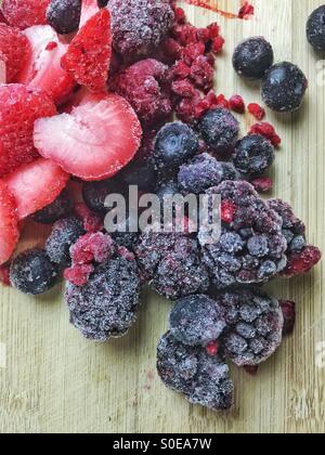 Frozen berries covered with frost on chopping board Stock Photo