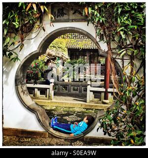 A tired little boy rests at the Lan Su Chinese Garden in Portland, Oregon. Stock Photo