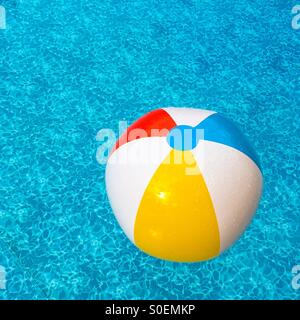 Beach ball in outdoor pool. (Yellow side dominant). Stock Photo