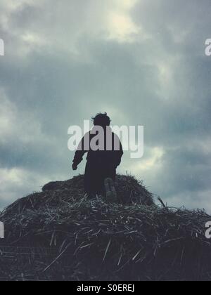 Little boy climbing a haystack Stock Photo