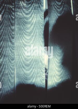Scared little boy hiding behind the curtains Stock Photo