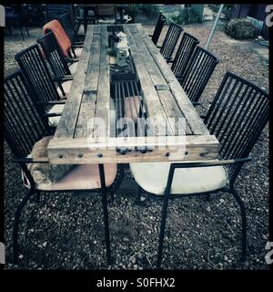 Ginger cat lying on chair at table in restaurant garden. Stock Photo