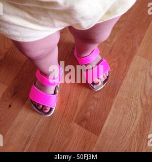 Small baby girl legs in pink sandals shoes Stock Photo