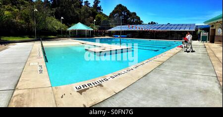 Panorama of a lifeguard watching over an empty Olympic size outdoor swimming pool in Summer. San Francisco Bay Area, California, USA. Stock Photo