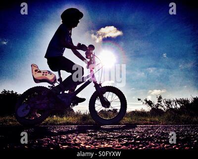 Young girl riding her bike in silhouette against the sun