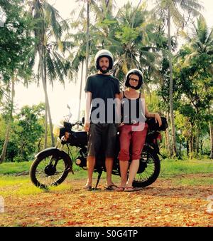 A couple with their motorbike, two people standing in front of a vintage motorcycle in a tropical location, Luang Prabang, Laos, Asia Stock Photo