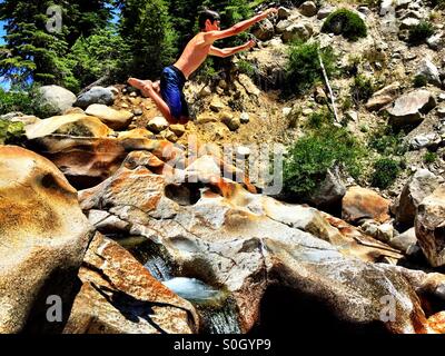 Boy midair leaping from top of a waterfall. Stock Photo