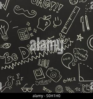 Drawing and writing on a black chalk board - be different, OMG, selfie, dream, and other pop culture references Stock Photo