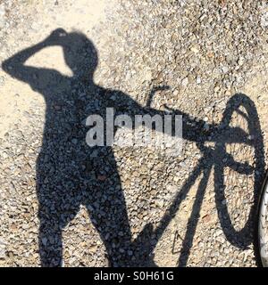 Shadow of a man drinking water standing beside a mountain bike in Tuscany, Italy. Stock Photo