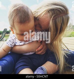 Young girl kissing and hugging her baby brother Stock Photo