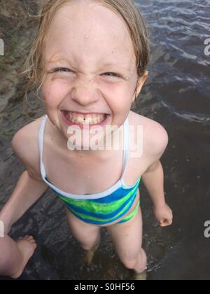 Young girl smiling and having fun grabbing her brother's leg in the river Stock Photo