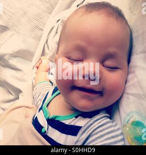 A 6 months old baby smiling in his sleep Stock Photo