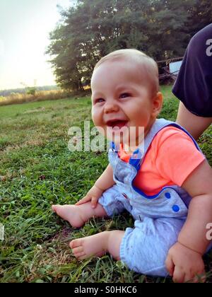 Smiling baby boy sitting on the grass Stock Photo