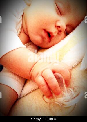 Sleeping baby boy holding his pacifier Stock Photo