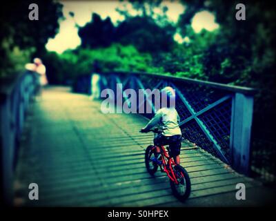 Boy cycling over bridge in Regent's Park, City of Westminster, Central London, England, United Kingdom, Europe Stock Photo
