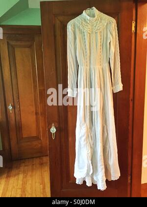 Antique wedding dress hanging on a door. Stock Photo