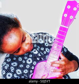 A young girl plays her guitar. Stock Photo