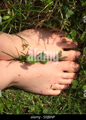 10 year old boy's wet , scraped feet on the green gras Stock Photo