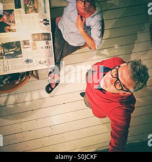 Man and woman in kitchen reading broadsheet newspaper Stock Photo