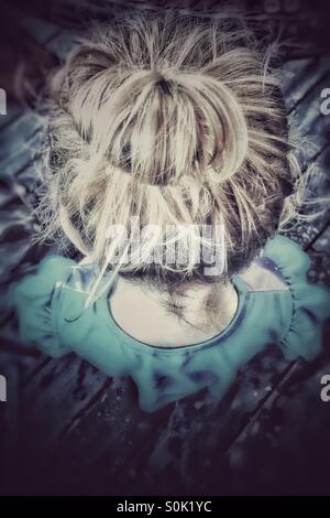 Looking down at toddler with her hair in a bun Stock Photo