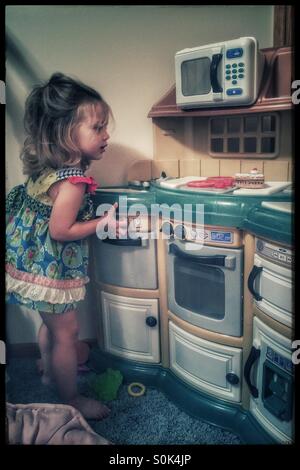 Little girl cooking in her play kitchen Stock Photo