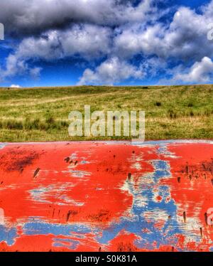 Old paint textures against green grass and cloudy blue sky Stock Photo