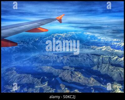 A View of an Aircraft Wing and Engines above The Alps Mountains, from an EasyJet flight as it travels over Switzerland. Photo Credit - © COLIN HOSKINS. Stock Photo