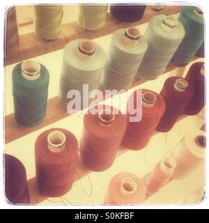 Colorful assortment of sewing thread spools organized by shade in a bright workspace Stock Photo