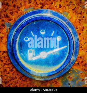 Blue coloured fuel gauge shown full, on an old rusty Stock Photo