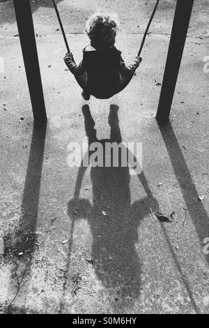Boy on swing with long shadows