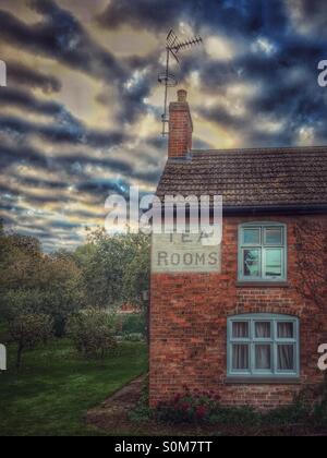 Traditional English cottage set in an orchard with a rea rooms sign painted in the wall Stock Photo