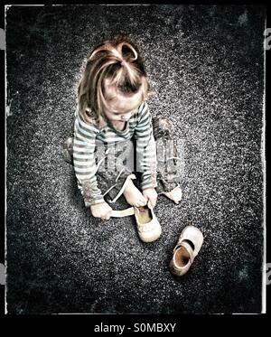 Little girl putting  her shoe on the wrong foot Stock Photo
