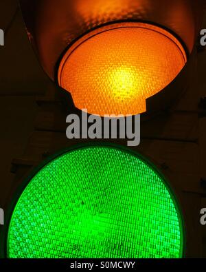 Close-up of illuminated amber yellow and green traffic signals. Stock Photo