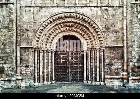 A heavy wooden church doorway with ornate stone carvings and pillars. Stock Photo