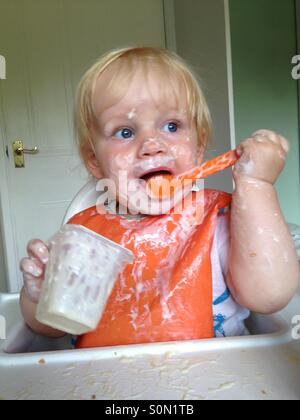 Baby making a mess eating a yoghurt Stock Photo