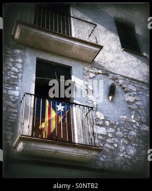 The Catalan flag of independence hangs from a balcony in the traditional town of Mora d'Ebre, with an artillery shell mounted on the wall, Catalonia, Spain. Stock Photo