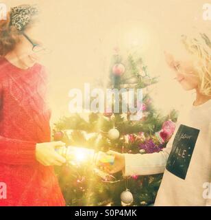 Two young children pulling a Christmas cracker in front of the Christmas tree Stock Photo