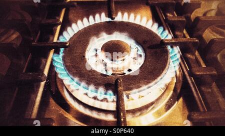 Double gas ring on a hob, lit and burning with a blue flame, in a vintage, grainy finish Stock Photo