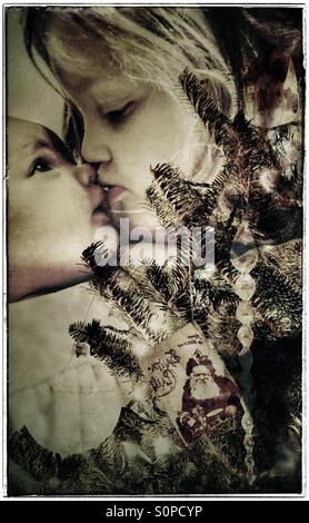 Toddler kissing her baby sister behind the Christmas tree (double exposure) Stock Photo