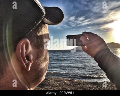 Man taking a photo with an iPhone Stock Photo